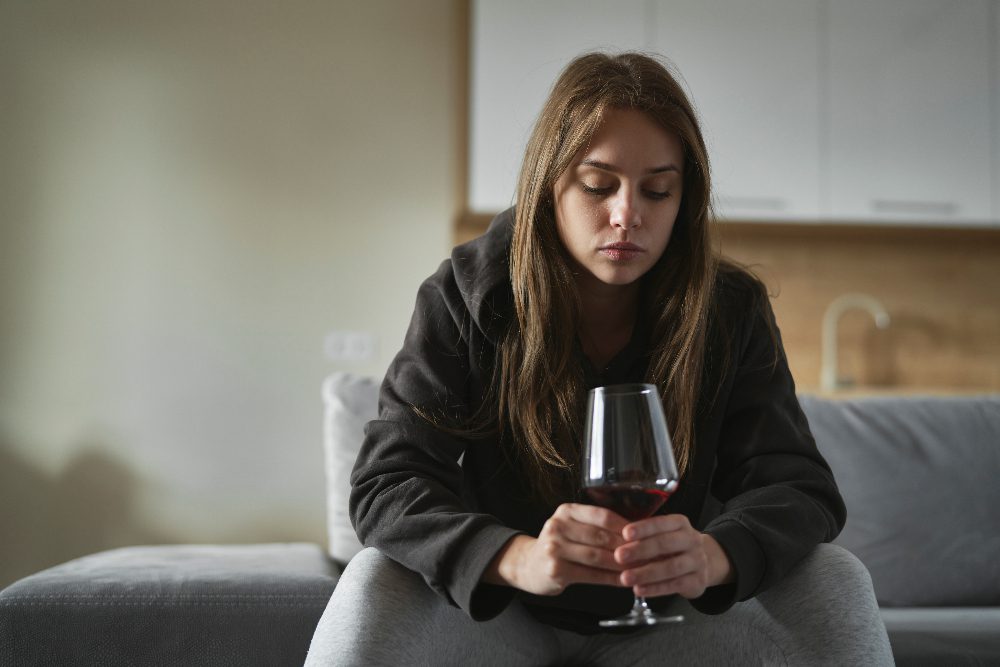 woman with glass of alcohol struggling with trauma and addiction