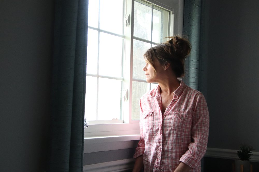 woman looking out window thinking about trauma